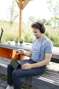 Young man using laptop while sitting on bench