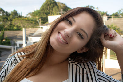 Portrait of smiling woman with hand in hair outdoors