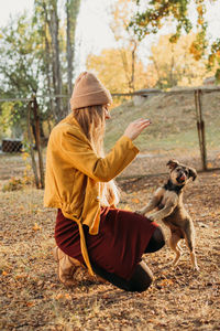 Rear view of woman with dog against trees