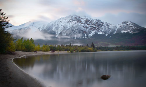 Scenic view of lake by snowcapped mountains against sky