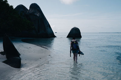 Rear view of backpack woman walking on shore
