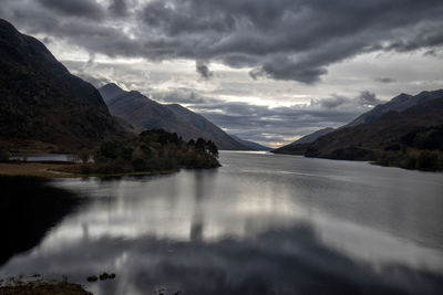 Scenic view of lake and mountains against cloudy sky