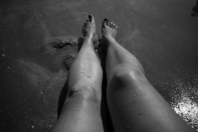 Low section of woman relaxing on wet shore