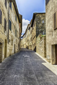 Empty road amidst buildings in city against sky