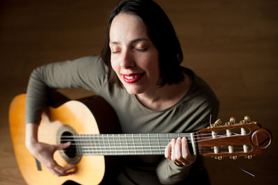 Woman playing guitar at home