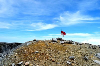 Low angle view of flag on rock against sky