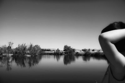 Close-up of woman by lake against clear sky