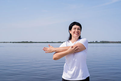 Portrait of a smiling young woman standing against sky