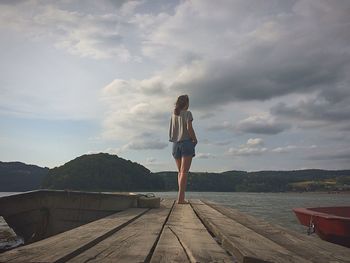 Rear view full length of woman standing on pier against lake