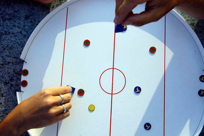 Playing a game of table hockey, two hands, blue and red tokens