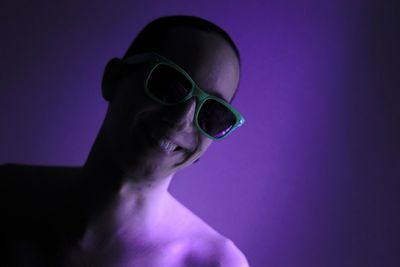 Portrait of young man wearing sunglasses against colored background