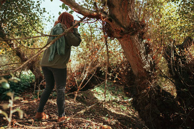 Young woman taking photos in the forest with an old analog camera