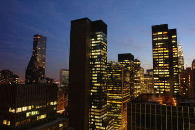 Illuminated buildings in city against sky at night