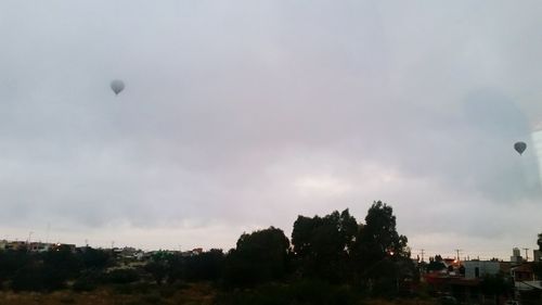 View of trees on landscape against clouds