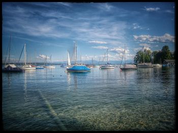 Boats in sea against cloudy sky