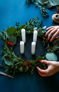 High angle view of woman holding wreath by candles