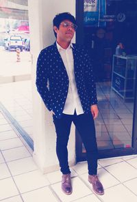 Portrait of young man looking away while standing on tiled floor