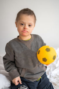 Portrait of cute baby boy playing with toy against white background