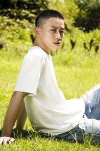 Side view of young man sitting on field