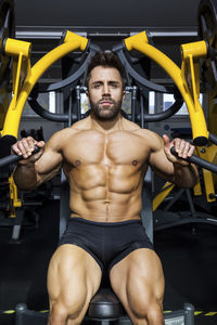 Portrait of man exercising on equipment at gym