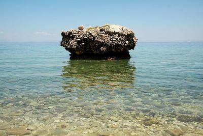 View of rock formation in sea against sky