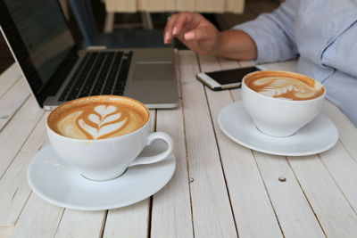 Businesswoman having cappuccino while using laptop on table at cafe