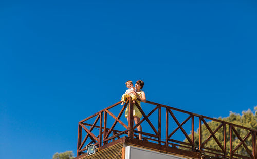 Low angle view of mother with standing against clear blue sky