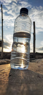 Close-up of glass bottle on table against sky
