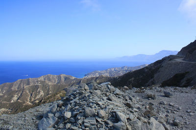 Scenic view of sea and mountains against clear blue sky