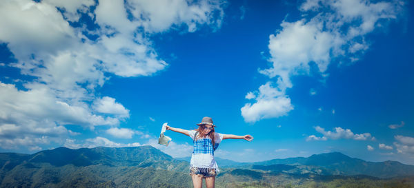 Rear view of woman standing on mountain against sky