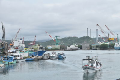 Sailboats moored in harbor against sky