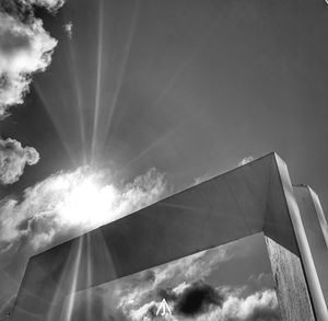 Low angle view of sunlight streaming through clouds