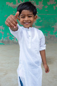 Portrait of smiling boy standing against wall