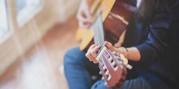 Midsection of man playing guitar