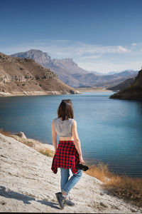 Rear view of woman standing on mountain against sky