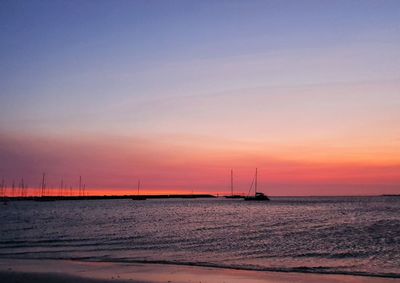 Sailboats in sea against sky during sunset