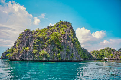 Boat approaching a limestone mountain of coron, palawan, philippines.