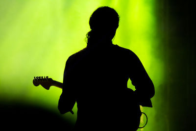 Rear view of silhouette man playing guitar