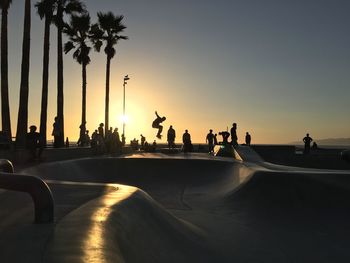 Silhouette of people at skateboard park against sky during sunset