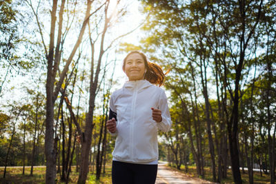 Low angle view of smiling woman jogging outdoors