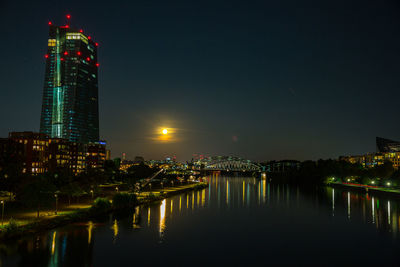 Illuminated european central bank  by river against sky at  moonrise at night