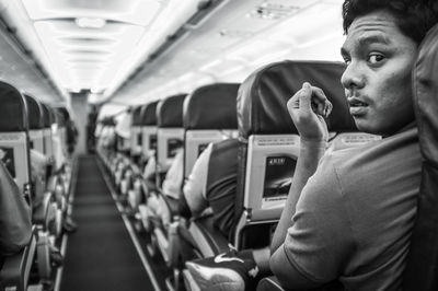 Rear view portrait of young man sitting in airplane