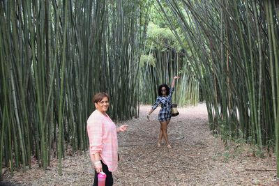 Full length of friends standing on field in forest