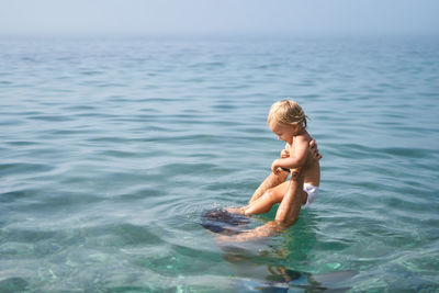 Side view of shirtless boy swimming in sea