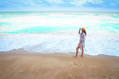 Woman standing on beach against sea