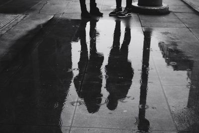 Low section of people standing on wet street during rainy season