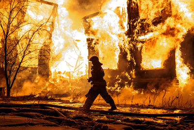 Firefighter walking by burning fire at night