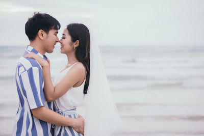 Young couple embracing while standing at beach