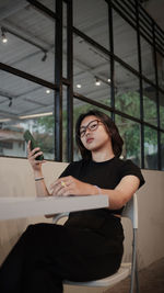 Young woman using mobile phone while sitting at cafe