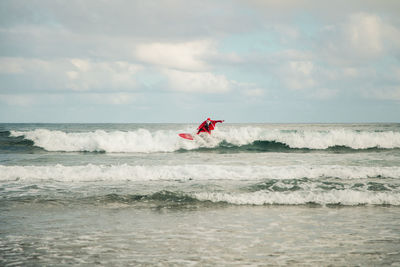 Man wearing santa costume surfing on sea against sky